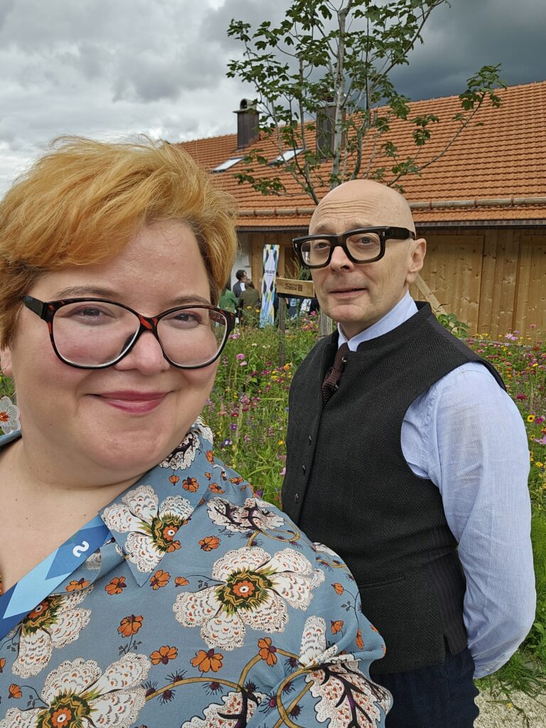 Selfie of Lisa a white woman with copper coloured hair, and Marcus a white man with no hair, both have big specs