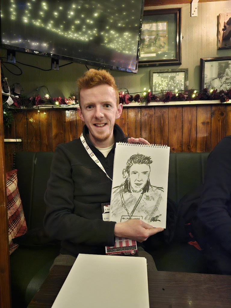 Man holding a sketch of him that isn't entirely unlike him